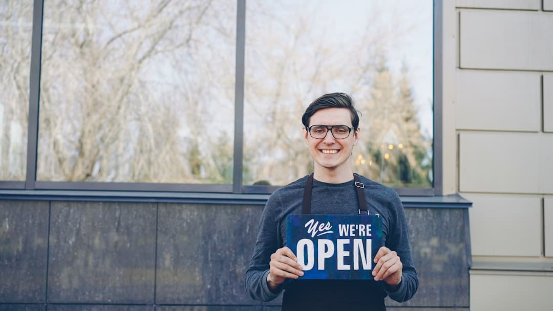 restaurant health code — A smiling man holds an "we're open" sign.